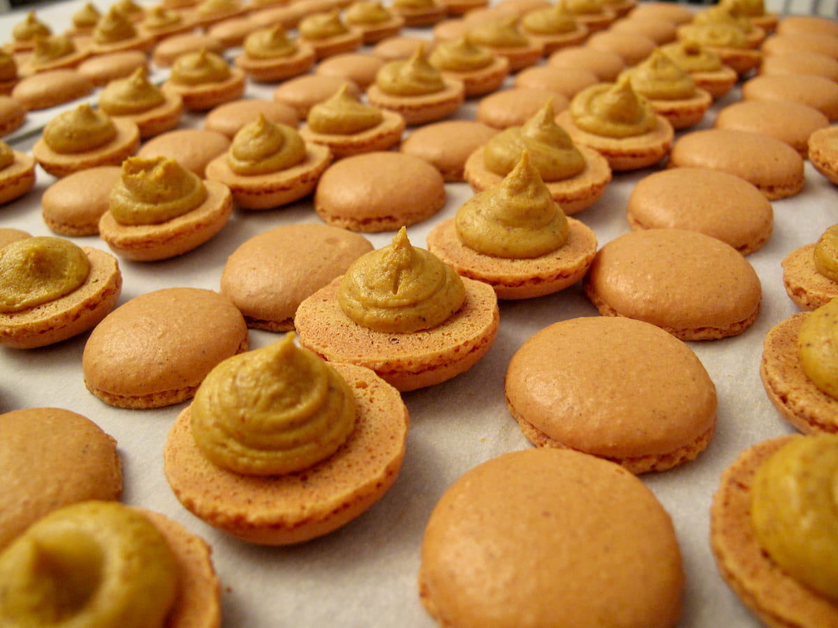 mini brown curry macaron shells with half of them piped with filling