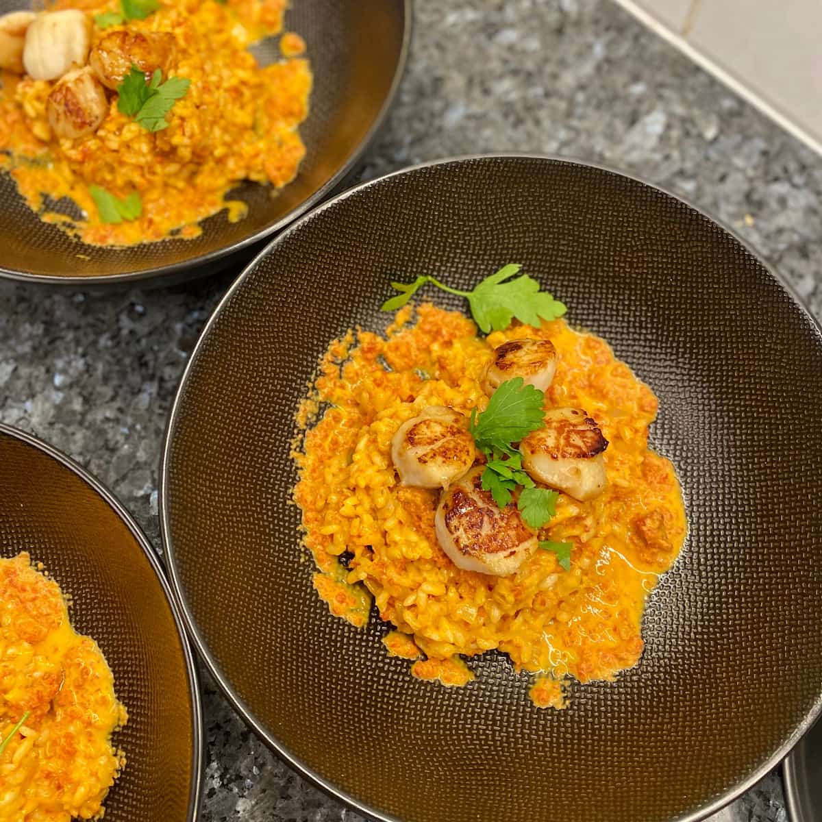 3 black giant bowls of creamy orange-coloured spicy risotto