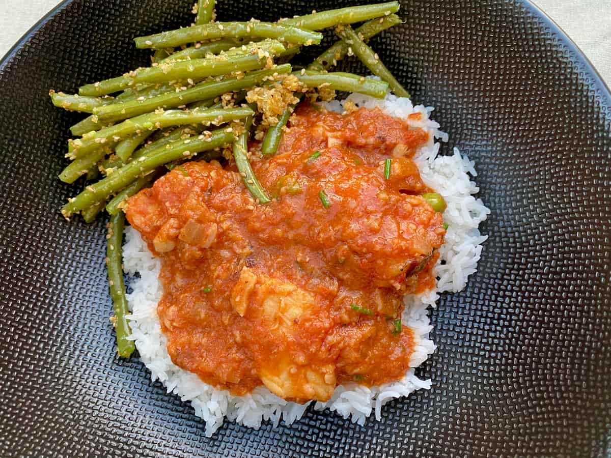 plate of French fish stew with tomatoes on a bed of rice with green beans