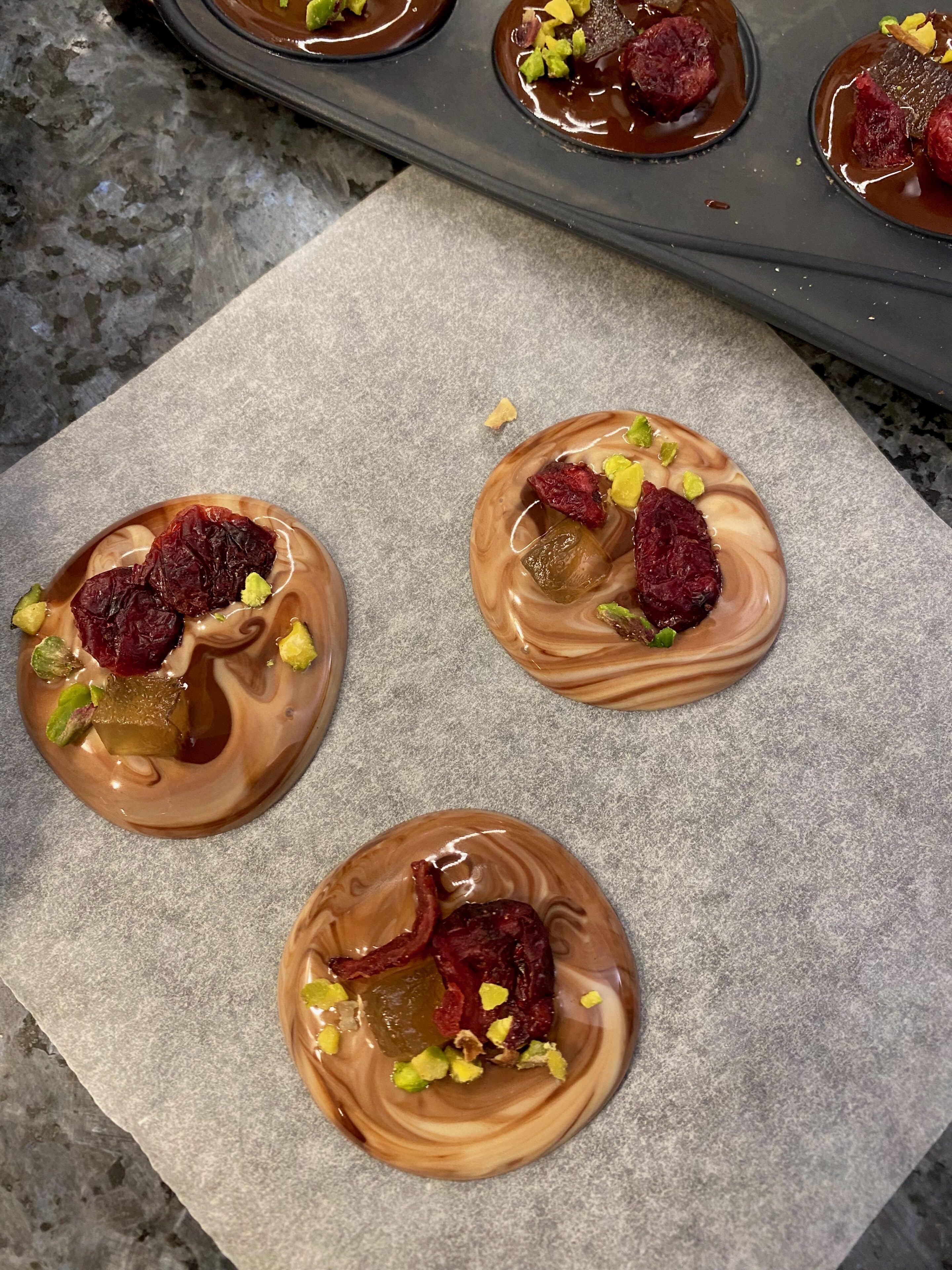 mendiants or chocolate disks with both dark and white chocolate topped with dried fruits and nuts