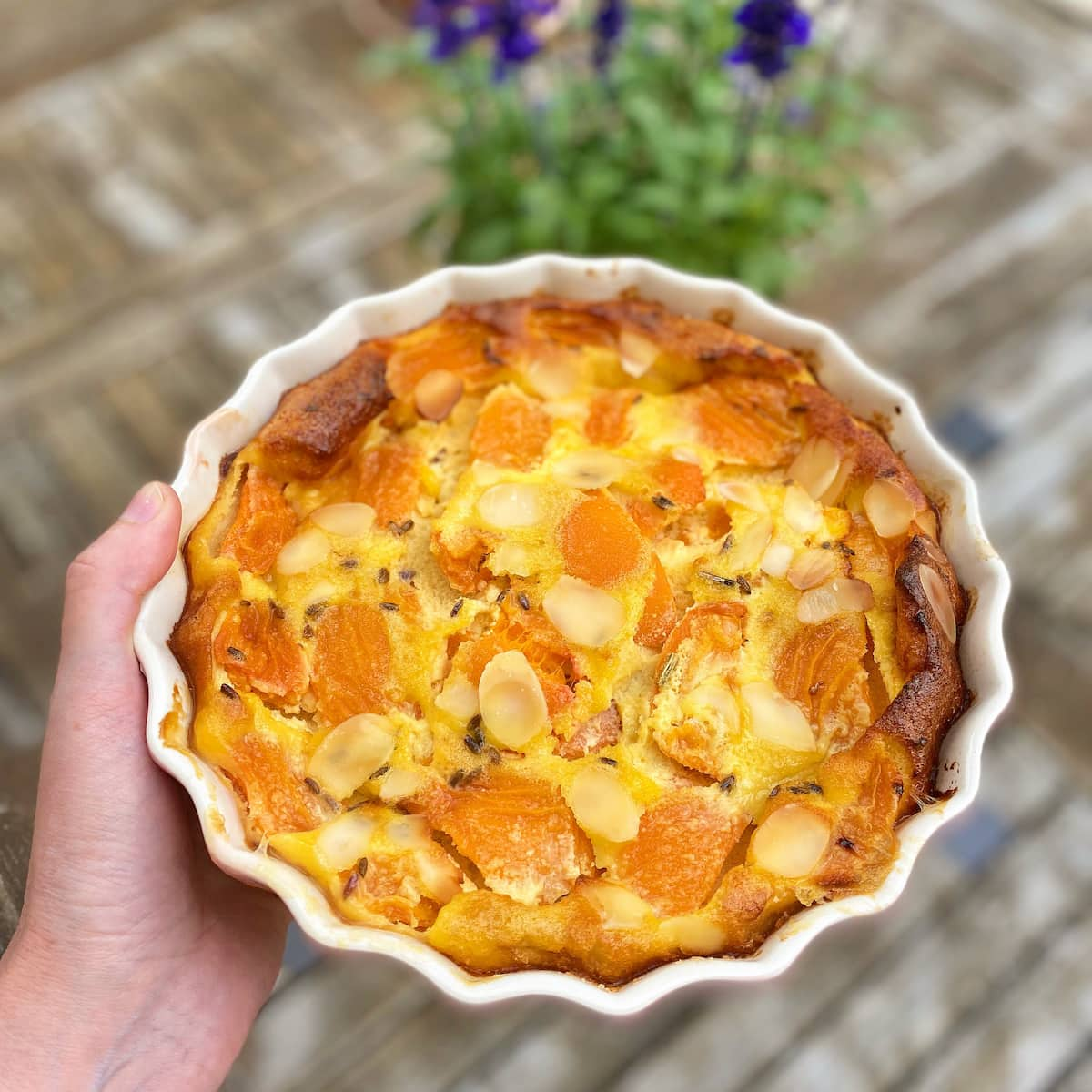 holding a dish with apricot baked custard topped with lavender