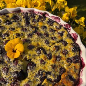 blueberry clafoutis dessert with lemon and yellow edible pansies