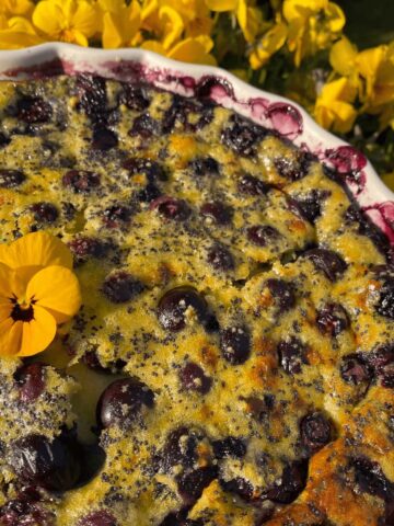 blueberry clafoutis dessert with lemon and yellow edible pansies