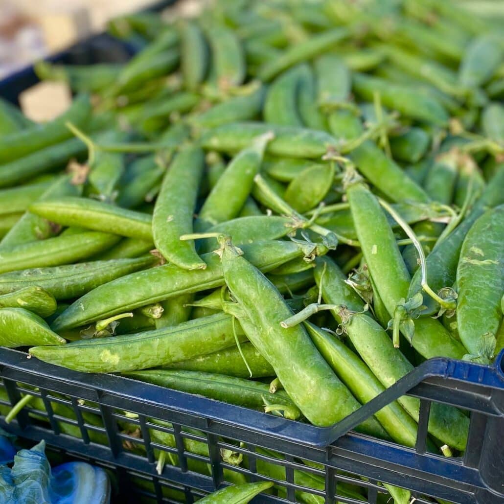 crate of fresh peas in their pods at the French market