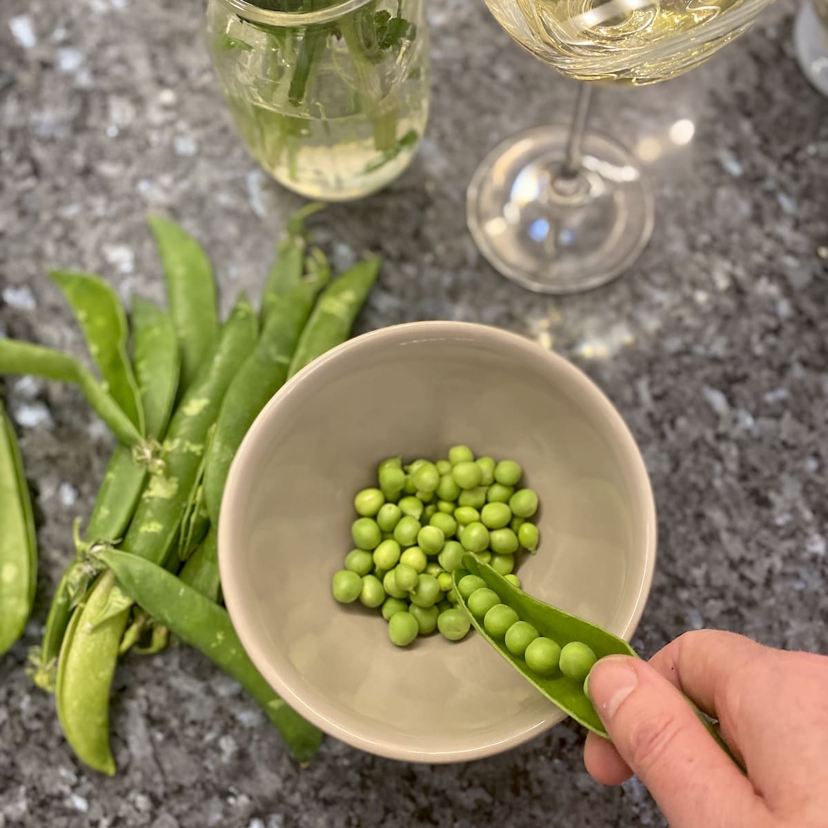 shelling fresh peas into a bowl