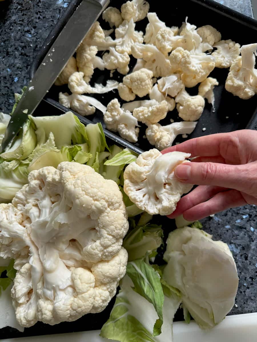 cutting off florets of a large cauliflower, leaves aside