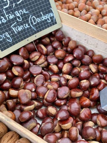 wooden crate of chestnuts in their shells at the French market