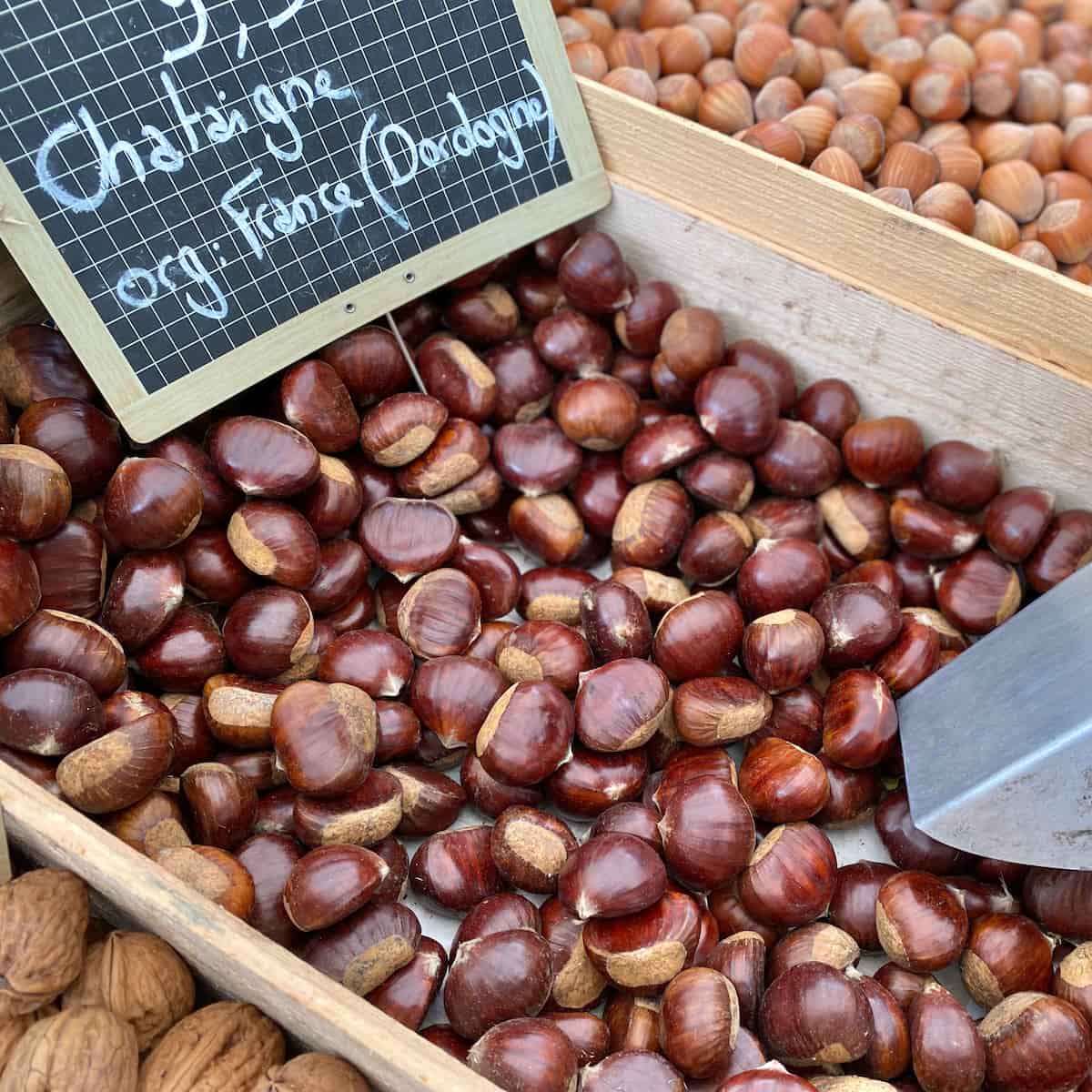 wooden crate of chestnuts in their shells at the French market