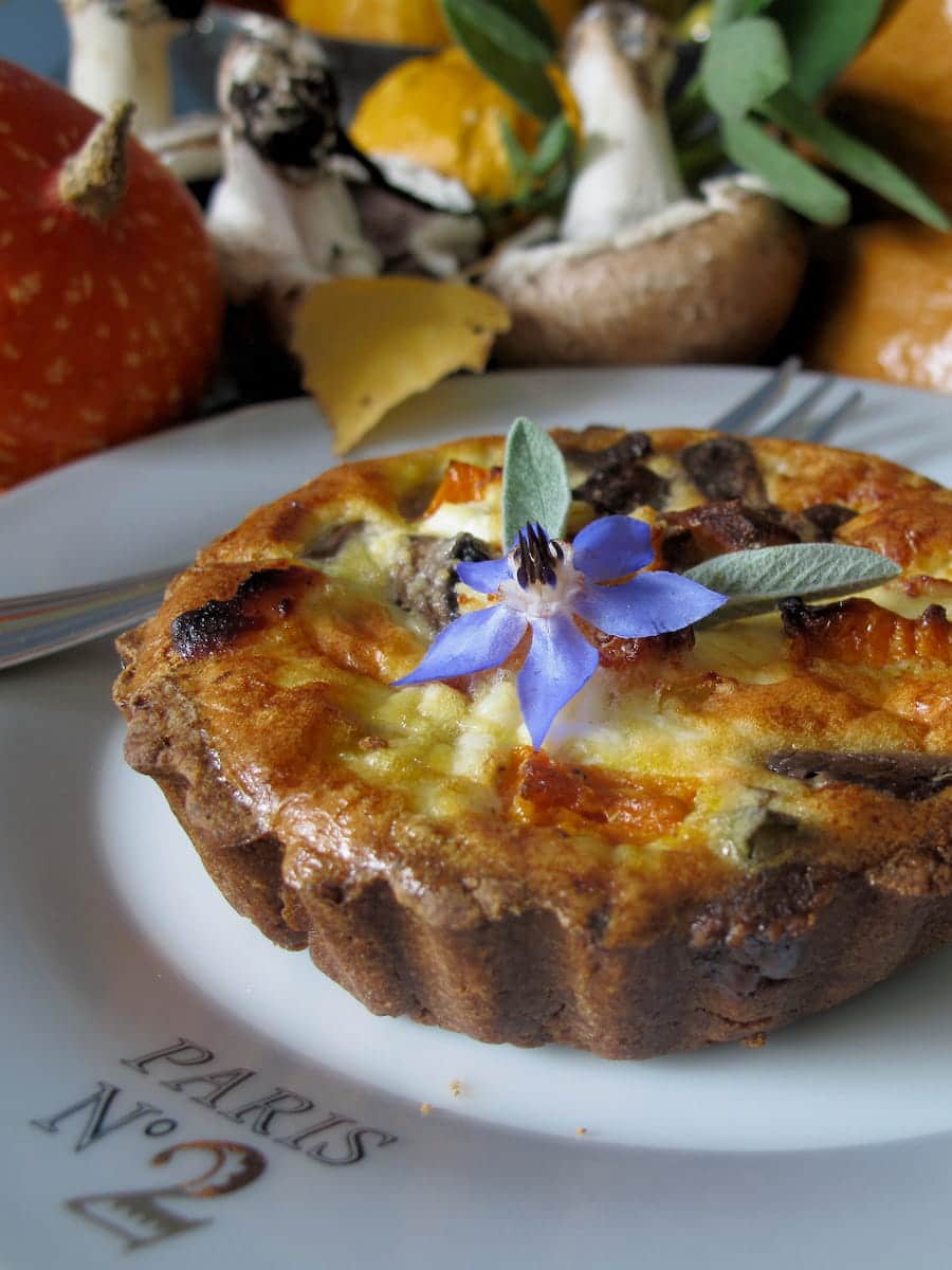 pumpkin and mushroom tart topped with an edible flower and sage