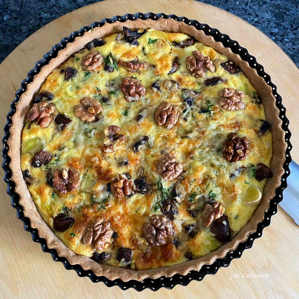 large round tart with pumpkin, mushrooms and topped with walnuts