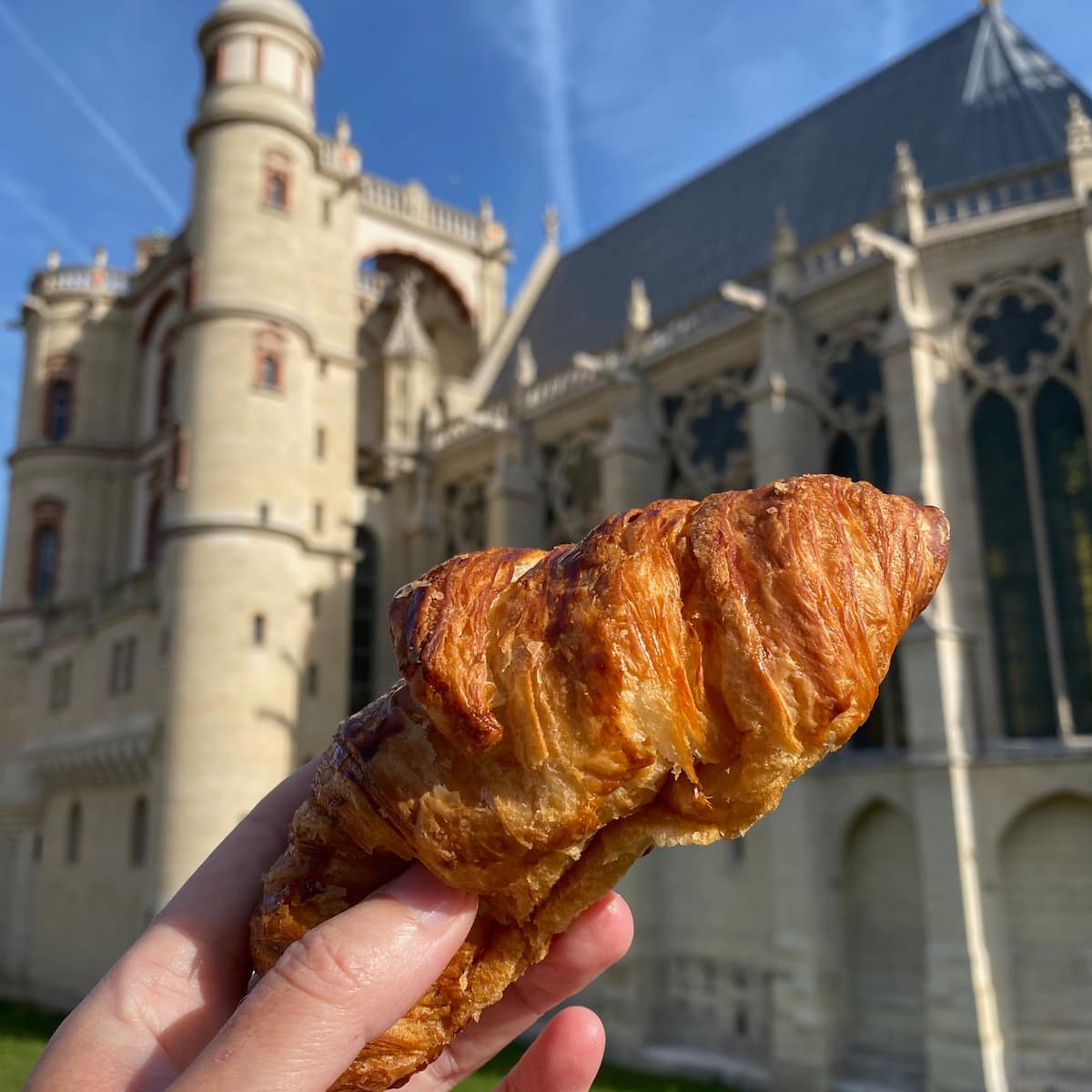 holding a croissant in front of a French castle
