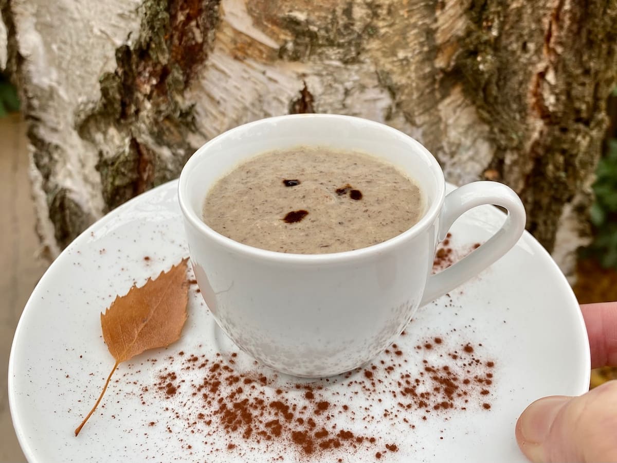 cup and saucer of mushroom soup dusted with cocoa powder 