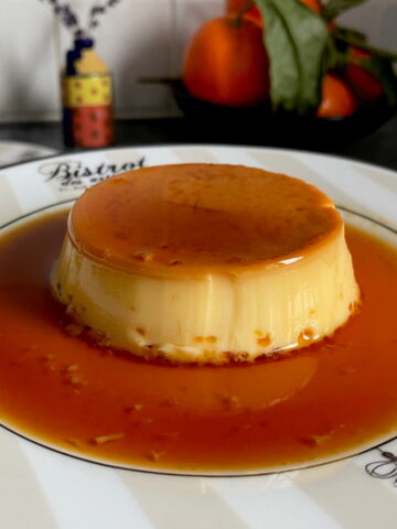 plate with eiffel tower and circle of caramel sauce around a shiny creme caramel