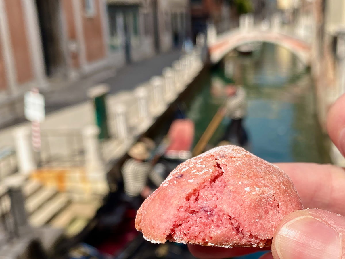 holding a pink macaron like pink cookie in Venice