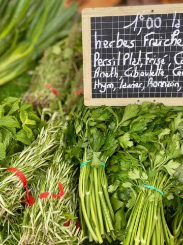 bunches of fresh herbs at the French market (with a sign in French saying herbes fraiches)