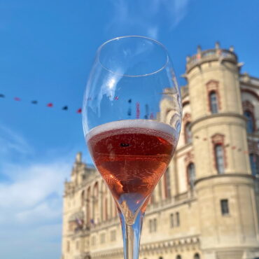 Champagne flute filled with a Kir Royal in front of a French chateau