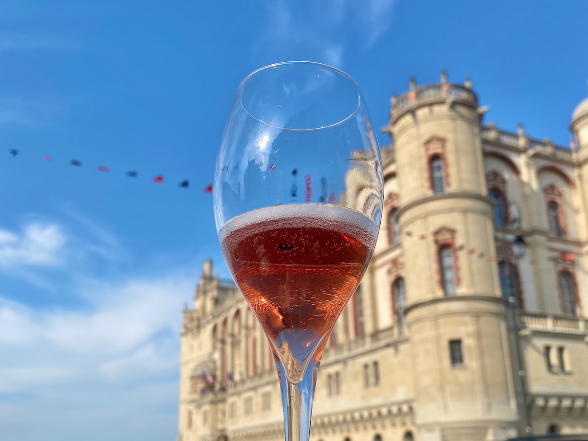 Champagne flute filled with a Kir Royal in front of a French chateau