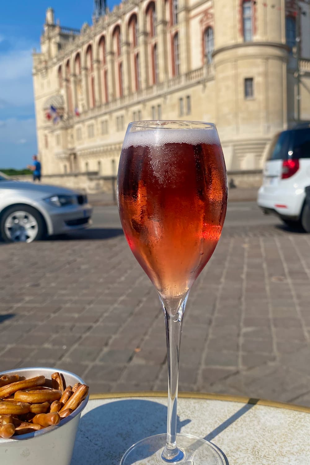 glass of Kir Royal drink in front of a chateau