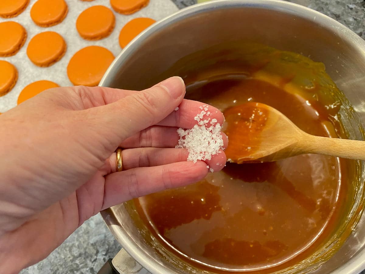 adding salt to a saucepan of caramel
