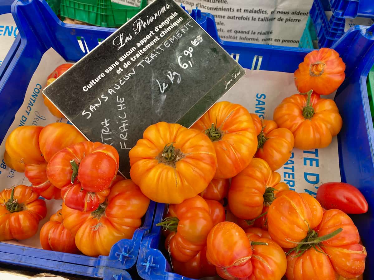large fresh tomatoes at the market, known as Poivrons in French, as the colour of red or orange peppers