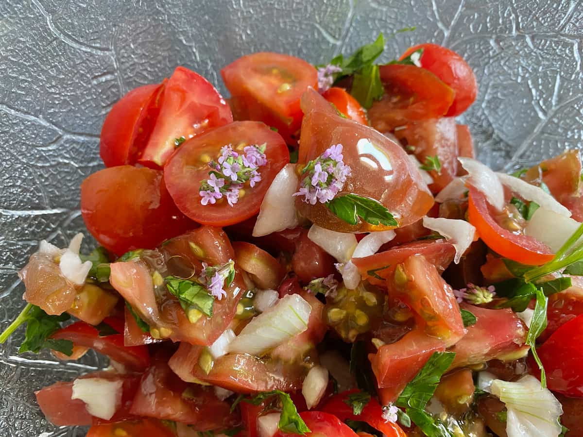 mixed tomato salad topped with fresh herbs and tossed in finely chopped onions and shiny olive oil