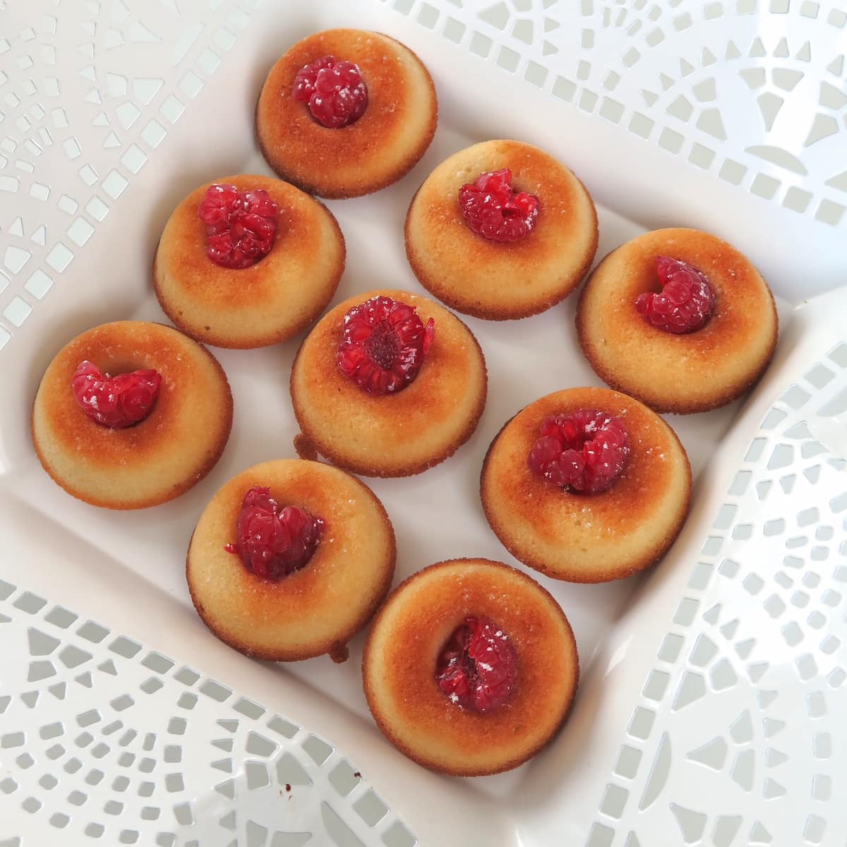 square white plate with golden buttery cakes filled with a raspberry