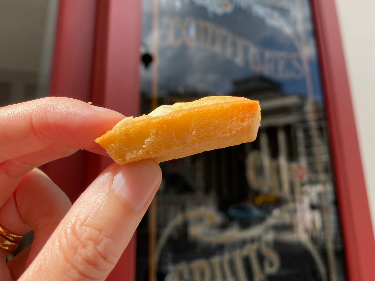 holding a golden bar shaped cake in front of a patisserie opposite the Paris stock exchange