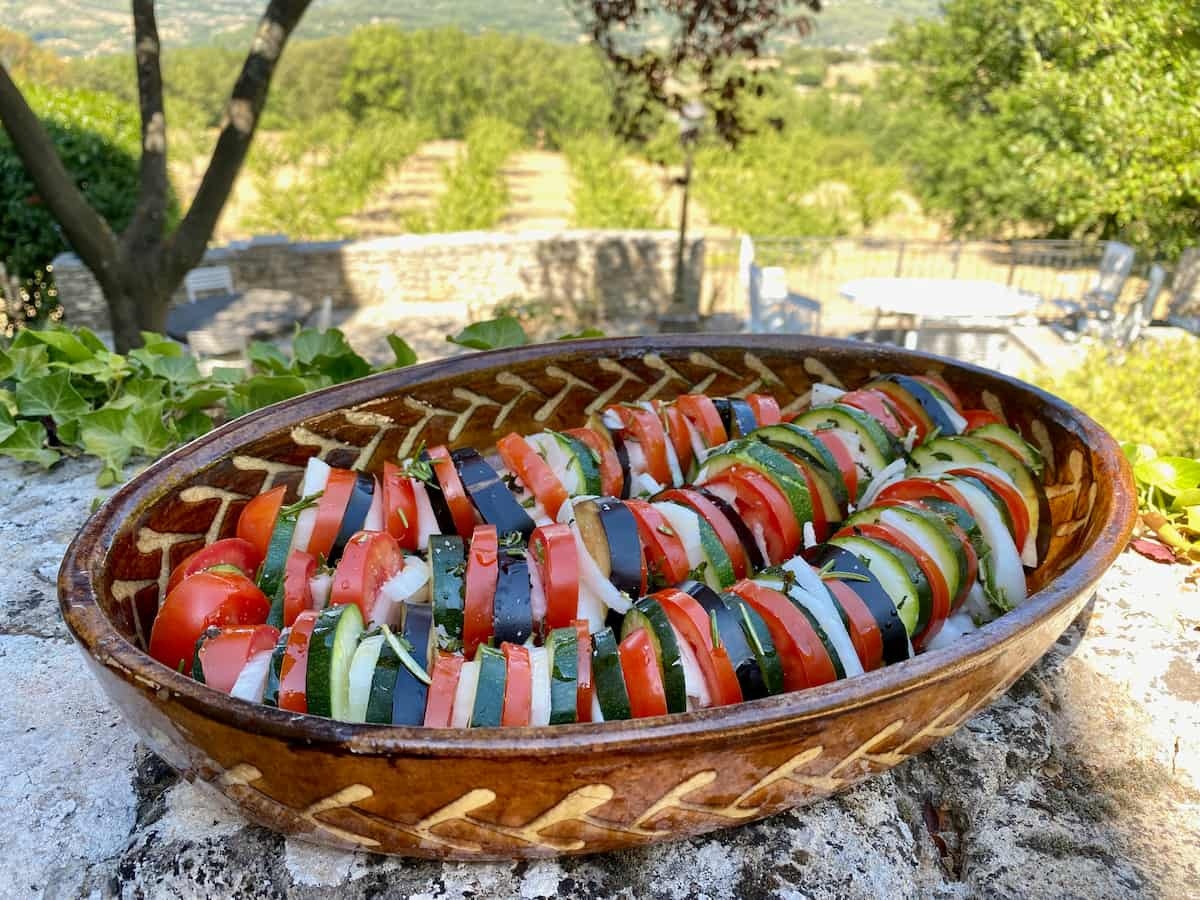 sliced summer vegetables in a dish ready to bake