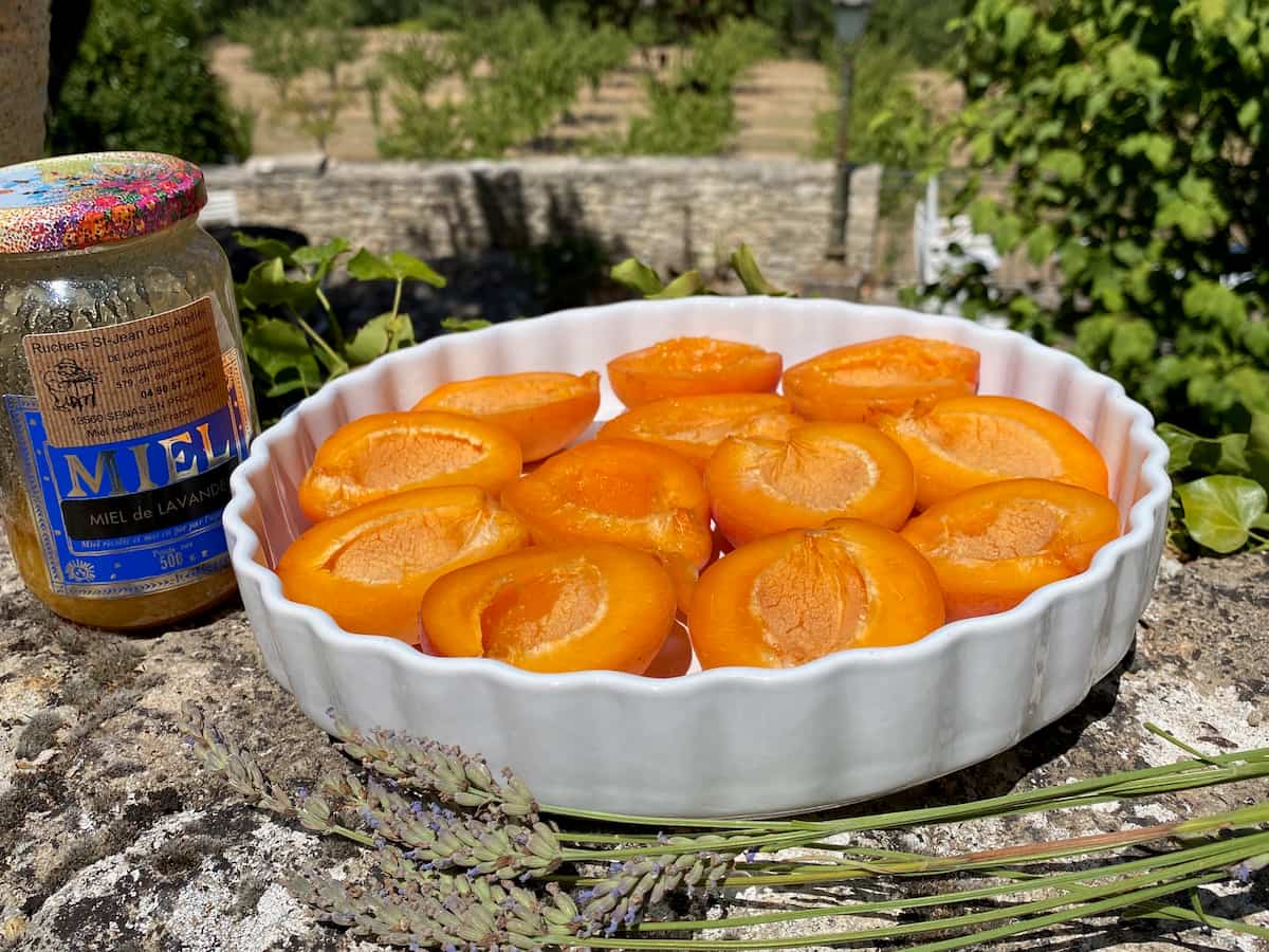 halved apricots in a dish with a pot of honey