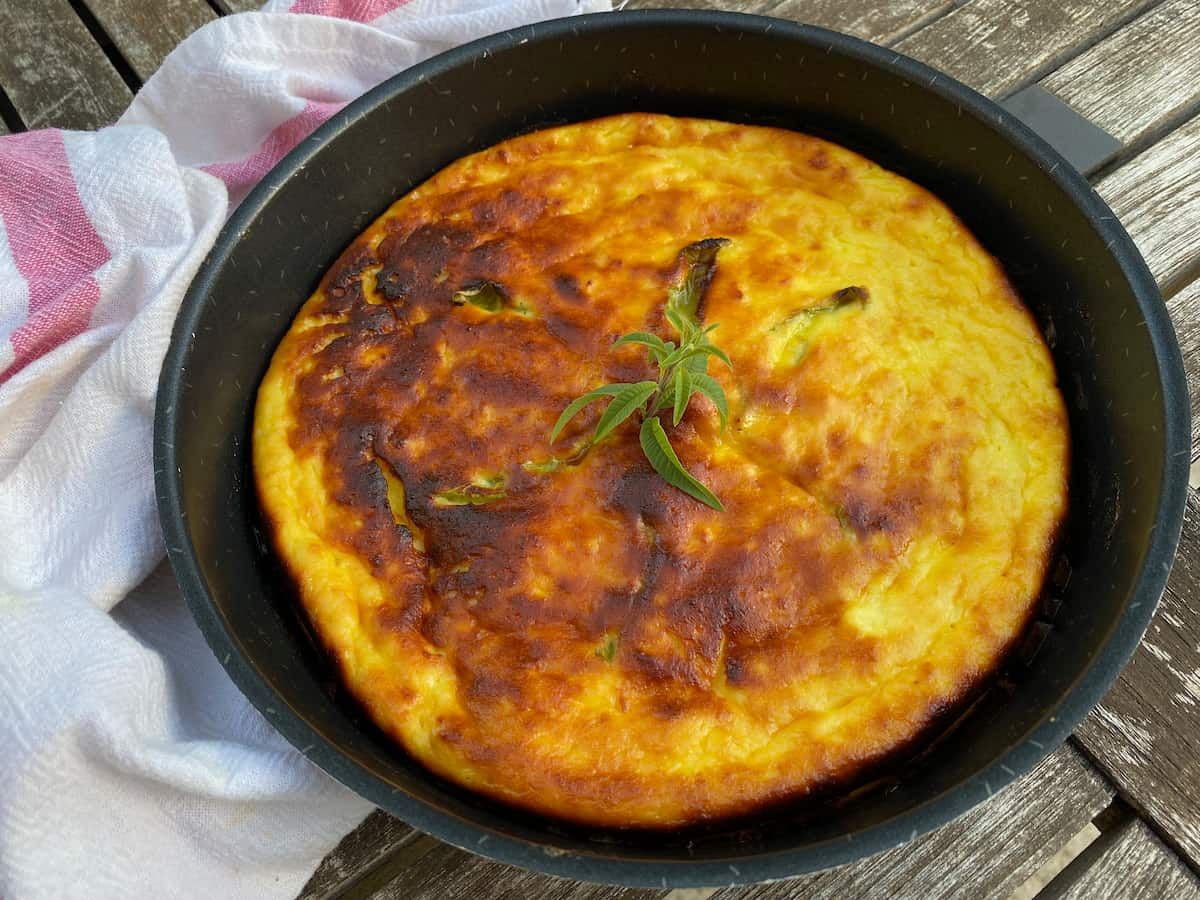 black cake tin with a bright golden brown cheesecake