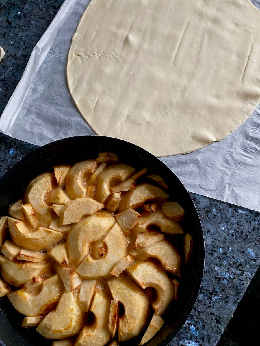 pan of caramelised apples next to a circle of uncooked pastry