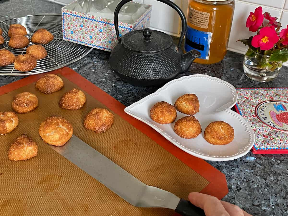 taking little baked cookies off a baking tray to cool