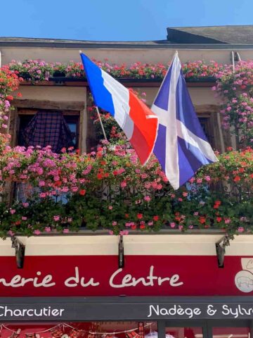 flags of France and Scotland together surrounded by flowers in a French town