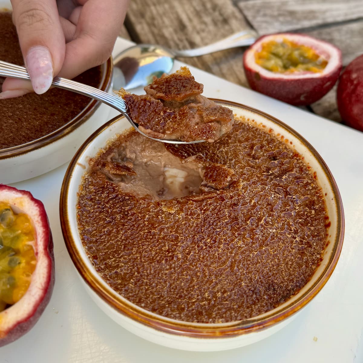 Red-planet-mars-creme-brulee cracking in to a milk chocolate crème brûlée showing a delicious set custard topped with a thin caramelised crust - served with halved passionfruits