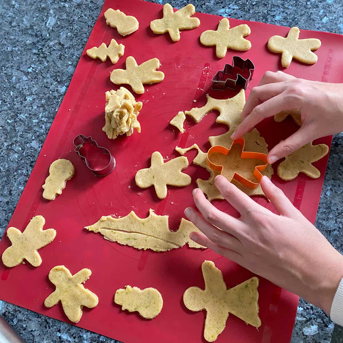 cutting out gingerbread men cookie shapes in rolled out dough