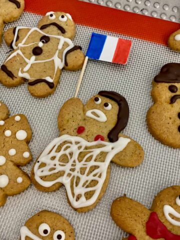 French Marianne decorated cookie holding a French flag surrounded by other gingerbread men