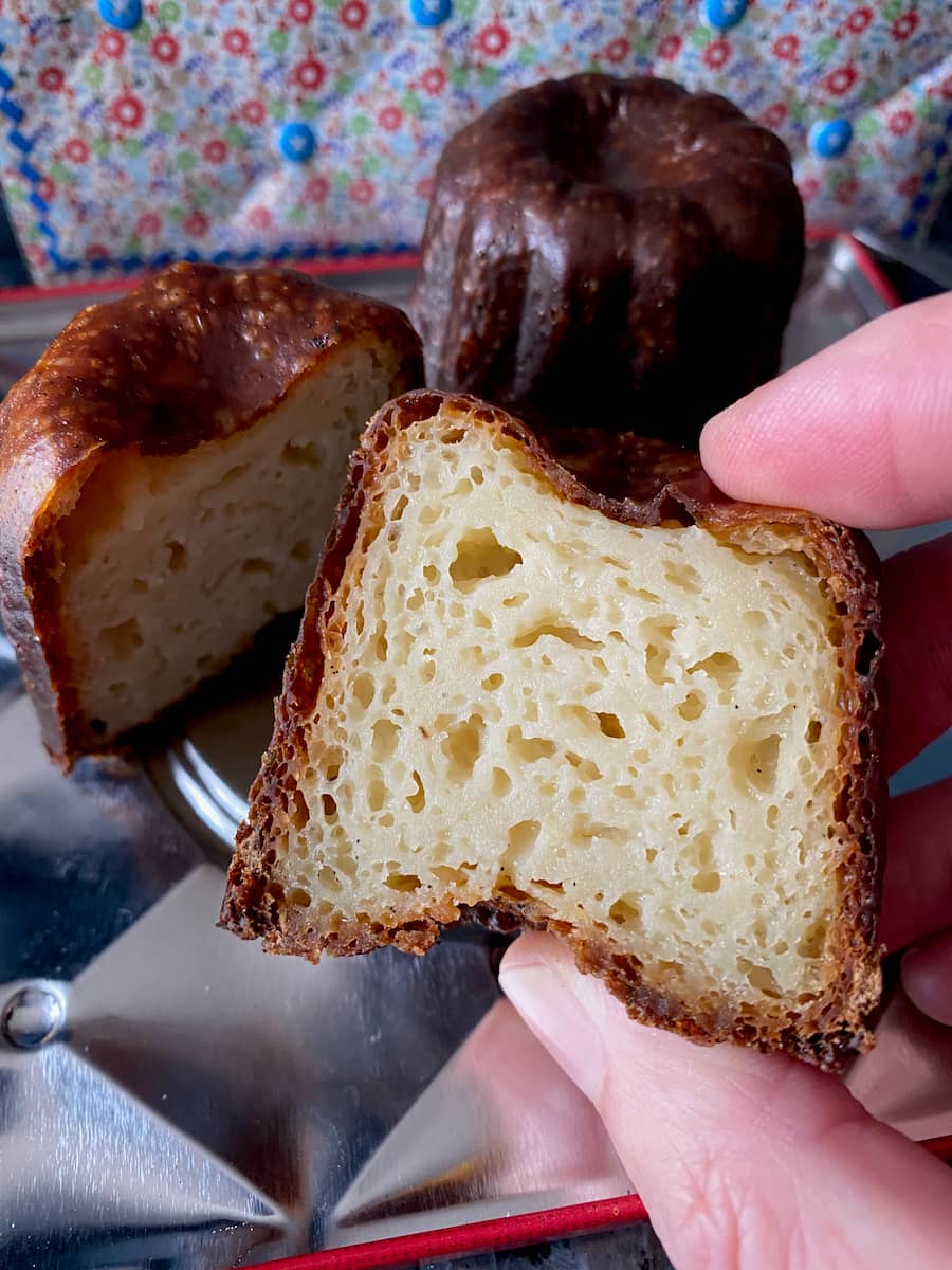 view of the inside of an authentic canelé with yellowy spongy interior and dark crispy exterior