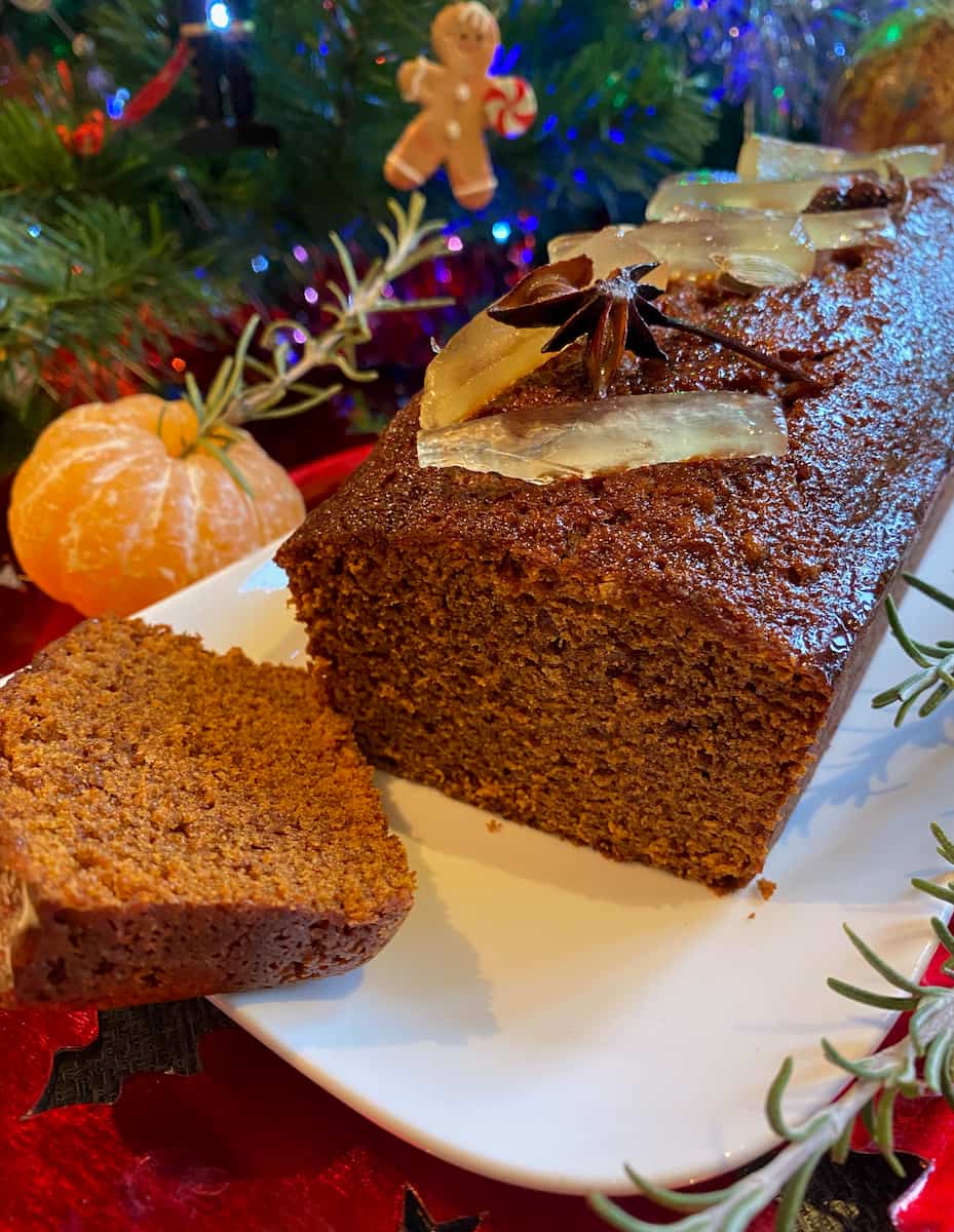 slice of dark brown glossy gingerbread topped with glacé ginger and star anise