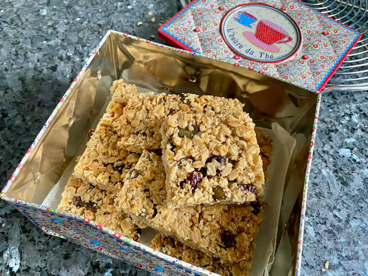 square golden cereal bars stacked together in a tin box with French writing for teatime