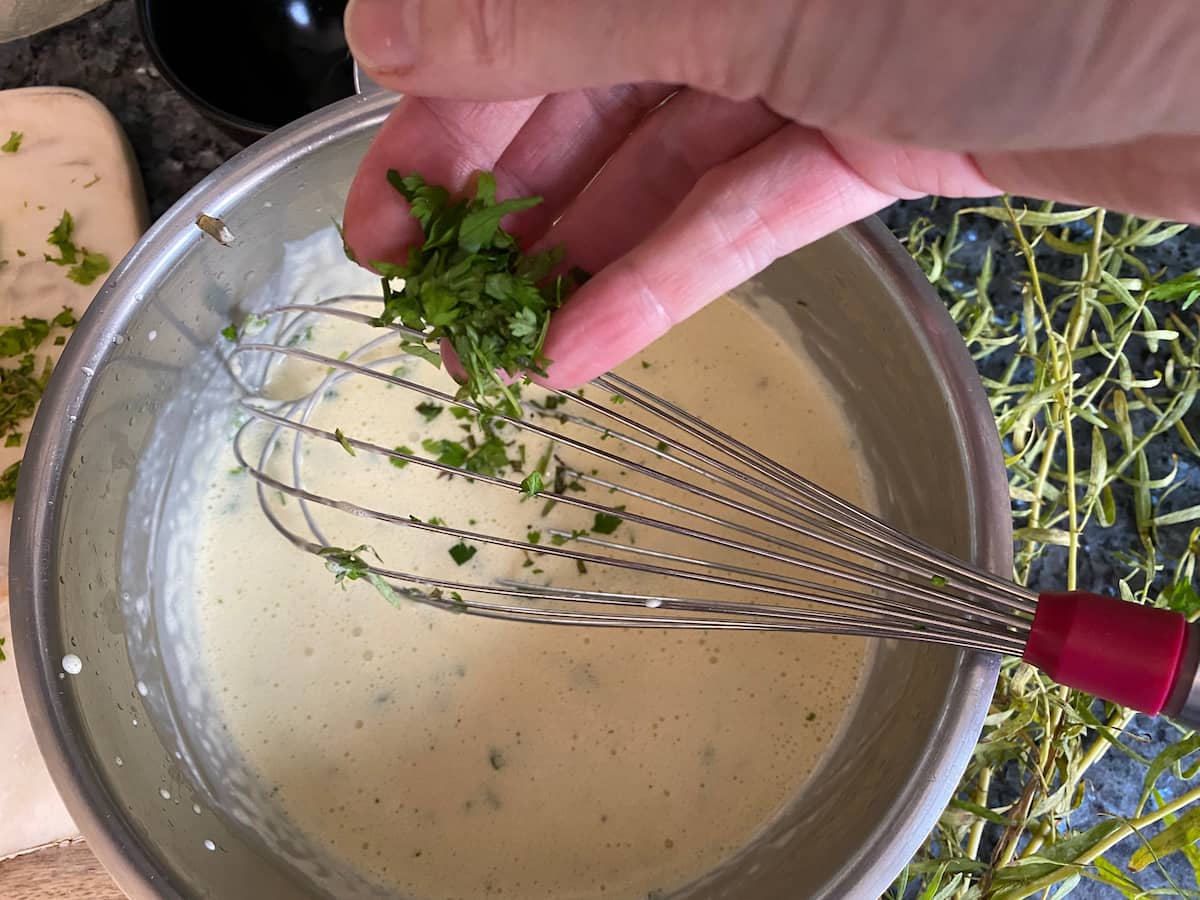 adding chopped fresh herb leaves while whisking a sauce