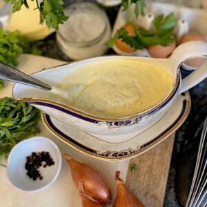 sauce boat filled with creamy Bearnaise surrounded by its classic ingredients