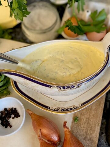 sauce boat filled with creamy Bearnaise surrounded by its classic ingredients