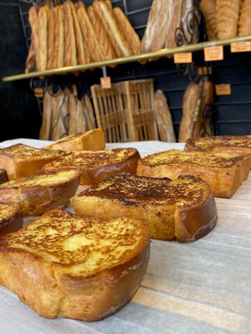 tray holding slices of toasted French toast or Pain Perdu in a boulangerie in France in front of baguettes