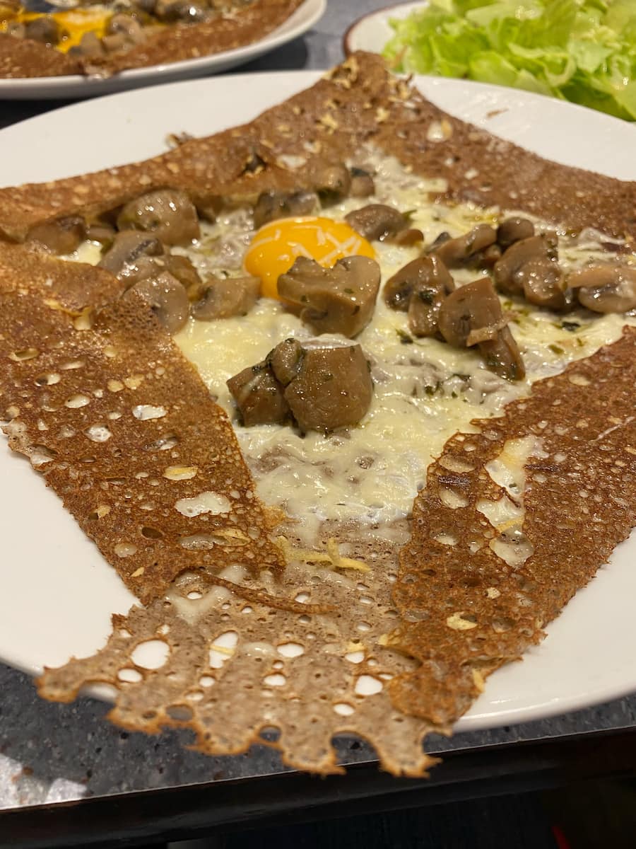 brown lace-like thin pancake filled with cheese, mushrooms and an egg