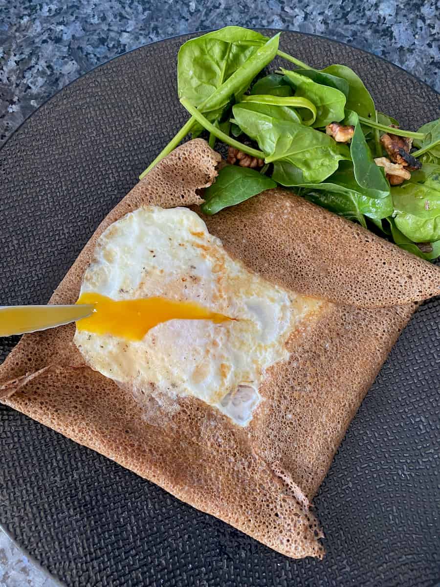 folded brown pancake like an envelope with a cooked egg in middle, with runny yolk