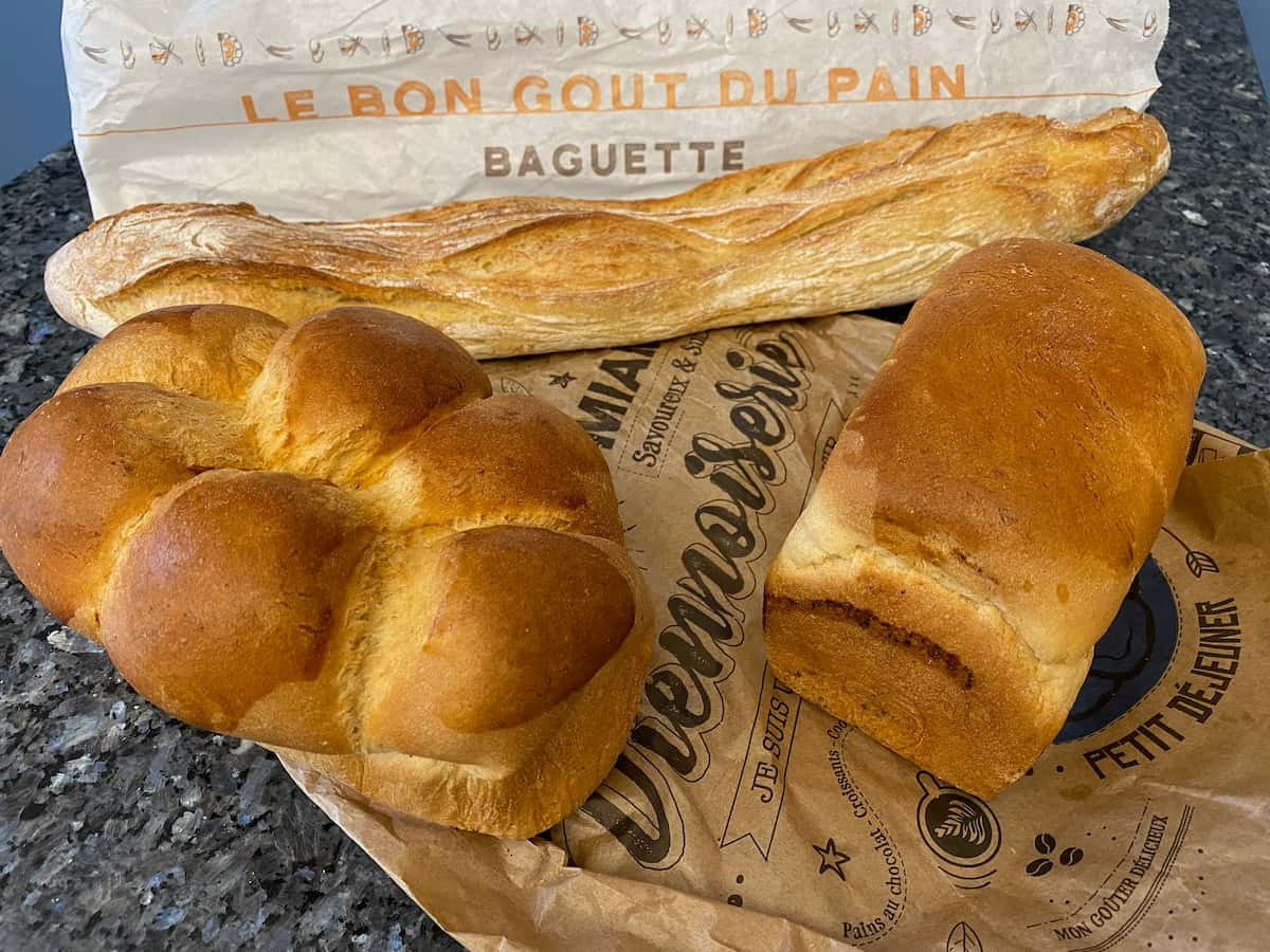 a French baguette stick, brioche loaf and loaf of white bread for slicing