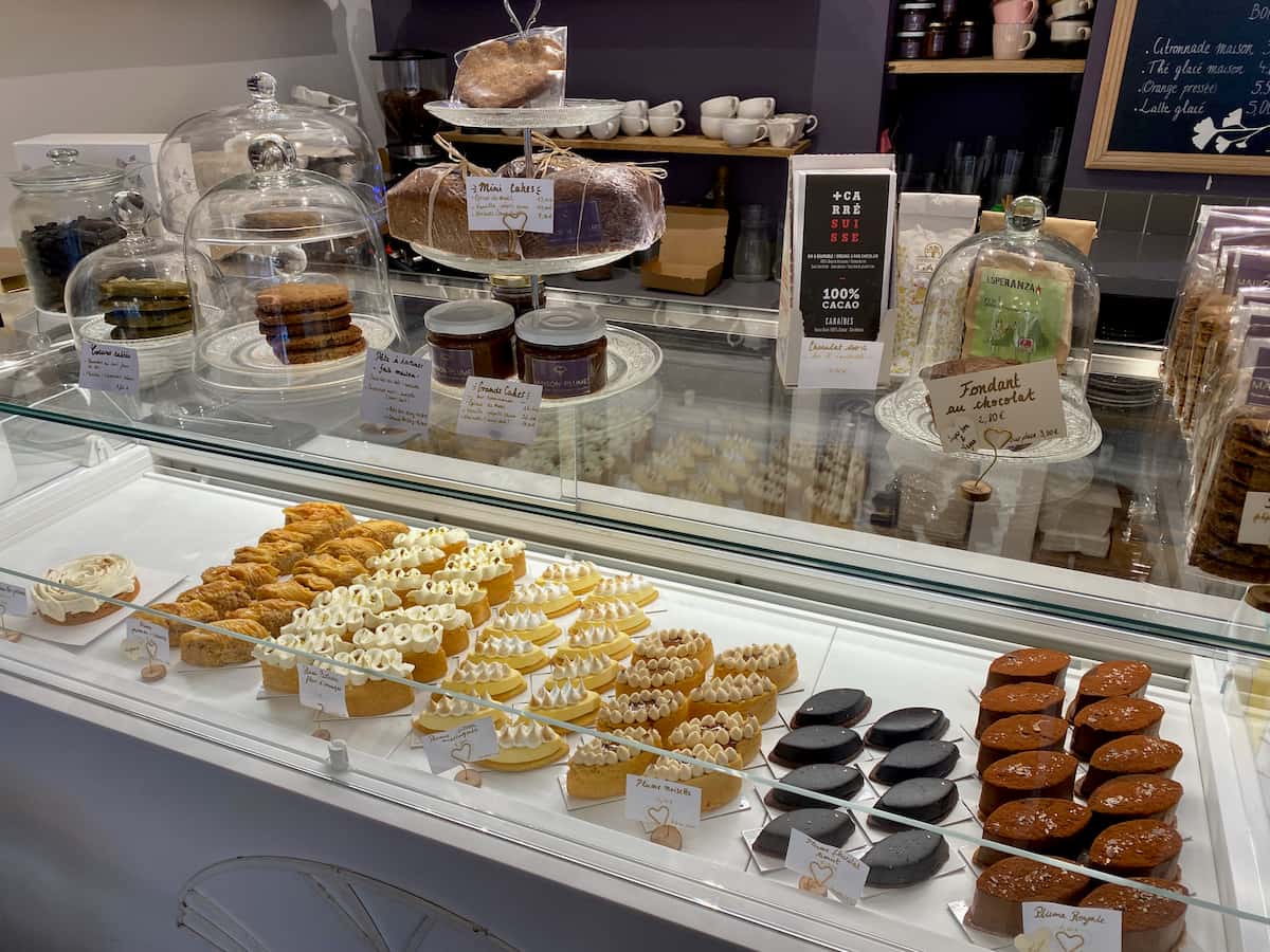patisseries in a glass case with cake stands and biscuits on the counter