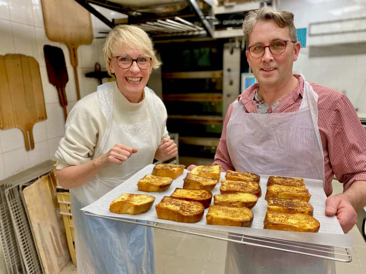 Laurent and Jill standing in a French bakery with a tray of pain perdu or French toast