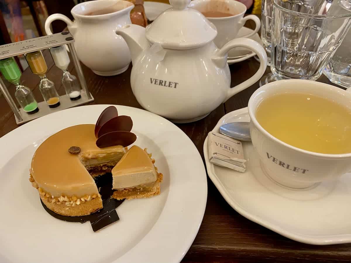 teapot, filled teacup inscribed with words, Verlet next to a sliced open French cake