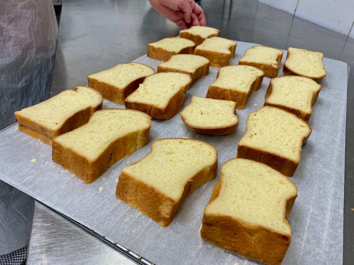 thick slices of white bread dipped in eggs and milk, laid out on a baking tray 